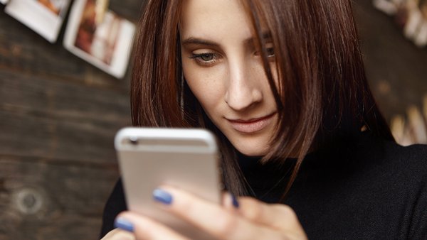close-up-shot-charming-young-european-woman-holding-generic-cell-phone-checking-email-newsfeed-via-social-media-using-online-apps