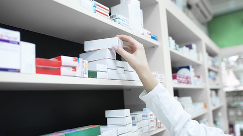 closeup-view-pharmacist-hand-taking-medicine-box-from-shelf-drug-store