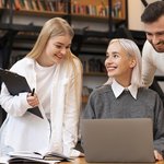 colleagues-studying-library-reading-from-laptop