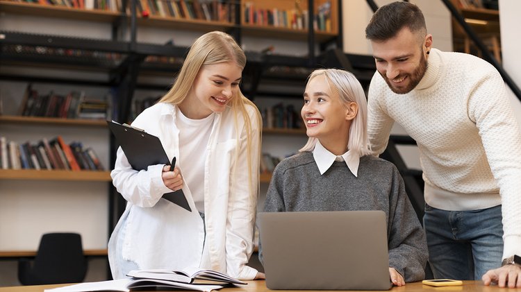 colleagues-studying-library-reading-from-laptop