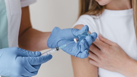 doctor-with-gloves-preparing-vaccine-woman