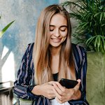 glamorous-woman-looking-phone-screen-while-sitting-office-indoor-shot-amazing-pretty-girl-resting-arm-chair