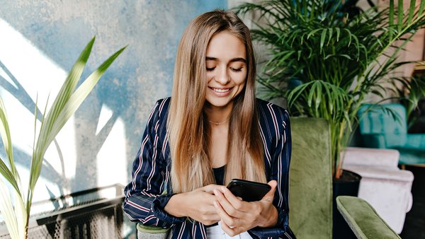 glamorous-woman-looking-phone-screen-while-sitting-office-indoor-shot-amazing-pretty-girl-resting-arm-chair