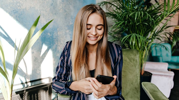 glamorous-woman-looking-phone-screen-while-sitting-office-indoor-shot-amazing-pretty-girl-resting-arm-chair