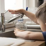 krupnym-planom-rebenok-napolnaet-butylku-vodoi