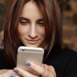 krupnym-planom-snimok-privlekatel-noi-molodoi-zensiny-s-pramymi-volosami-brunetki-smotrasei-na-ekran-svoego-telefona