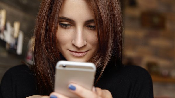 krupnym-planom-snimok-privlekatel-noi-molodoi-zensiny-s-pramymi-volosami-brunetki-smotrasei-na-ekran-svoego-telefona
