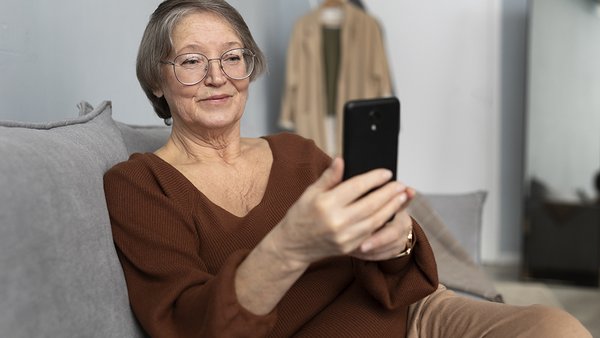 scastlivaa-pozilaa-zensina-s-pomos-u-smartfona-v-gostinoi-sovremennoi-kvartiry