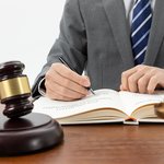 snimok-krupnym-planom-celoveka-pisusego-v-knige-s-molotkom-na-stole