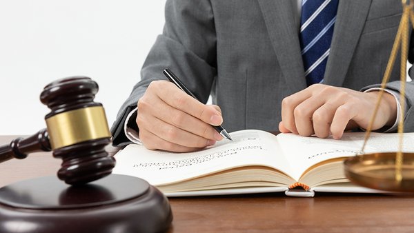 snimok-krupnym-planom-celoveka-pisusego-v-knige-s-molotkom-na-stole