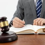 snimok-krupnym-planom-celoveka-pisusego-v-knige-s-molotkom-na-stole