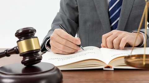 snimok-krupnym-planom-celoveka-pisusego-v-knige-s-molotkom-na-stole