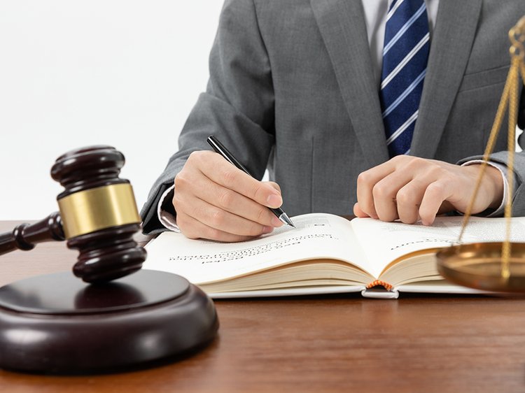 snimok-krupnym-planom-celoveka-pisusego-v-knige-s-molotkom-na-stole