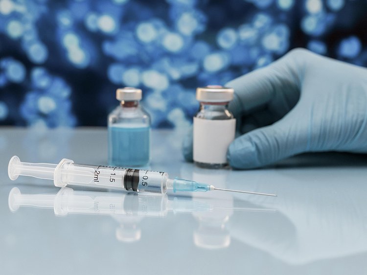 spric-i-flakon-s-vakcinoi-na-stole-s-rukoi-v-percatke