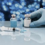 spric-i-flakon-s-vakcinoi-na-stole-s-rukoi-v-percatke