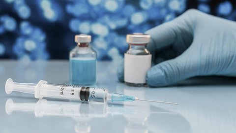 spric-i-flakon-s-vakcinoi-na-stole-s-rukoi-v-percatke