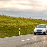white-suv-drives-wet-highway-curve-open-countryside-safe-driving