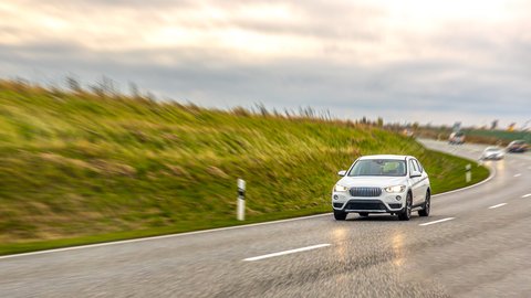white-suv-drives-wet-highway-curve-open-countryside-safe-driving
