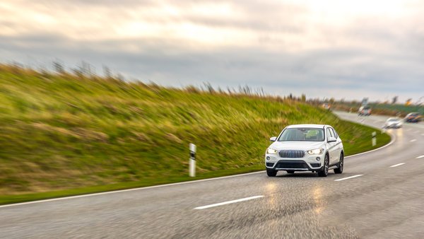 white-suv-drives-wet-highway-curve-open-countryside-safe-driving