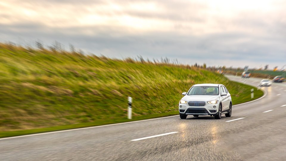 white-suv-drives-wet-highway-curve-open-countryside-safe-driving