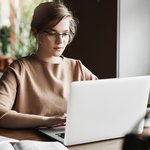 work-lifestyle-business-concept-good-looking-focused-european-female-trendy-glasses-sitting-cafe-near-laptop-working-notebook-surrounded-with-books-making-notes
