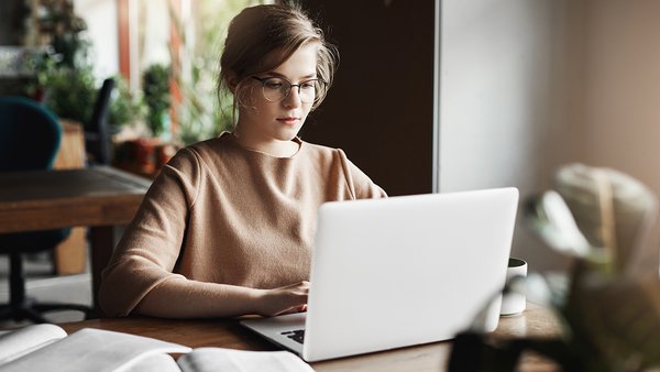 work-lifestyle-business-concept-good-looking-focused-european-female-trendy-glasses-sitting-cafe-near-laptop-working-notebook-surrounded-with-books-making-notes