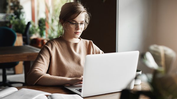 work-lifestyle-business-concept-good-looking-focused-european-female-trendy-glasses-sitting-cafe-near-laptop-working-notebook-surrounded-with-books-making-notes