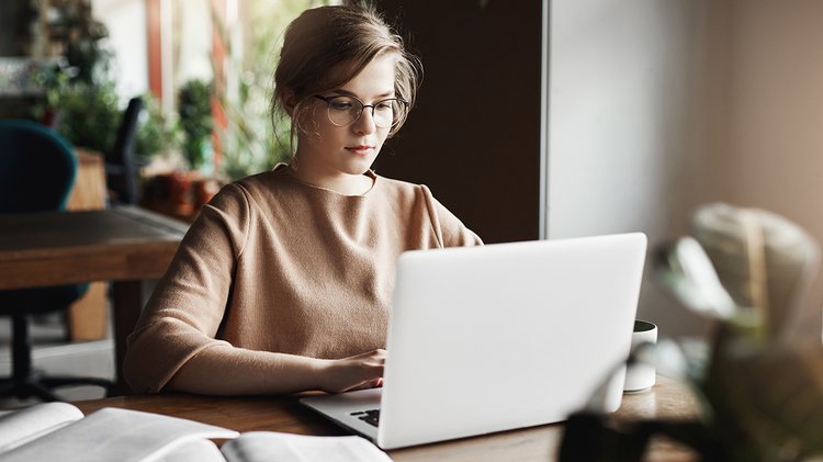 work-lifestyle-business-concept-good-looking-focused-european-female-trendy-glasses-sitting-cafe-near-laptop-working-notebook-surrounded-with-books-making-notes