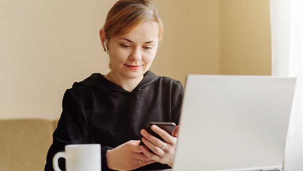 zensina-ispol-zua-noutbuk-i-mobil-nyi-telefon-dla-ego-udalennoi-raboty-na-domu