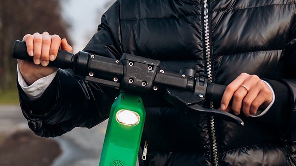 zensina-v-kurtke-na-elektriceskii-skuter-v-osennii-park